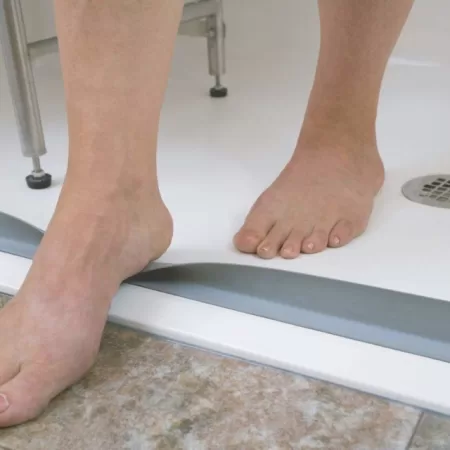 “Foot stepping on LG collapsible grey water stopper in a shower, demonstrating its flexibility and functionality.”
